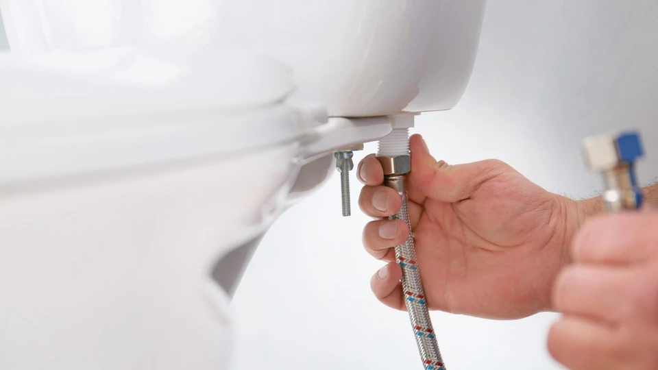 Technicien en gants noirs effectuant une maintenance sur installation de chauffage avec clé à molette