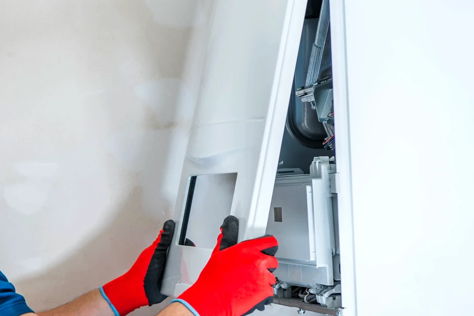 Technicien en tenue professionnelle effectuant une maintenance préventive sur une pompe à chaleur ou une chaudière gaz intérieure, utilisant des outils de diagnostic et de contrôle dans un environnement résidentiel. Le professionnel procède à une inspection visuelle et à des mesures techniques sur l'équipement thermique, illustrant la rigueur et la prévention des pannes.