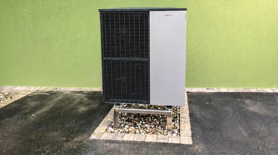 Deux techniciens en uniforme bleu travaillent sur une unité extérieure de climatisation dans un environnement urbain